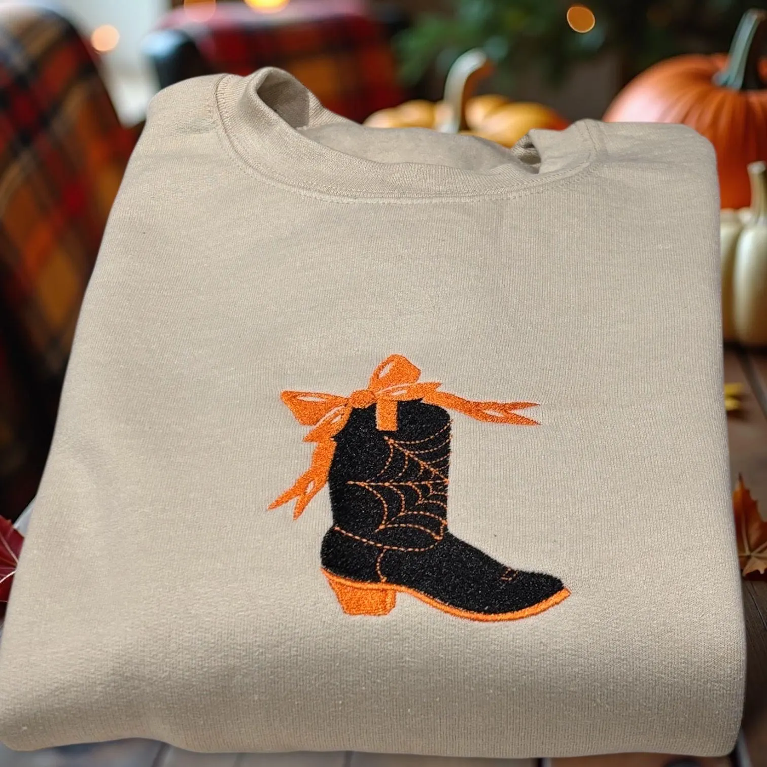 Embroidered spooky cowboy boot with cobweb and bow sweatshirt or hoodie. Western Halloween clothing.